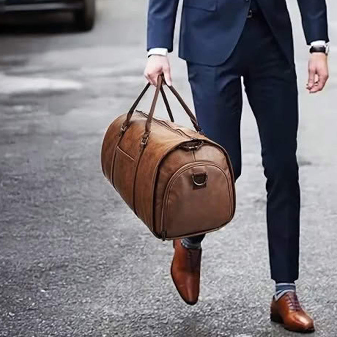 Le sac fourre-tout étanche pour homme par Wanderer, tenu à la main par un mannequin en costume